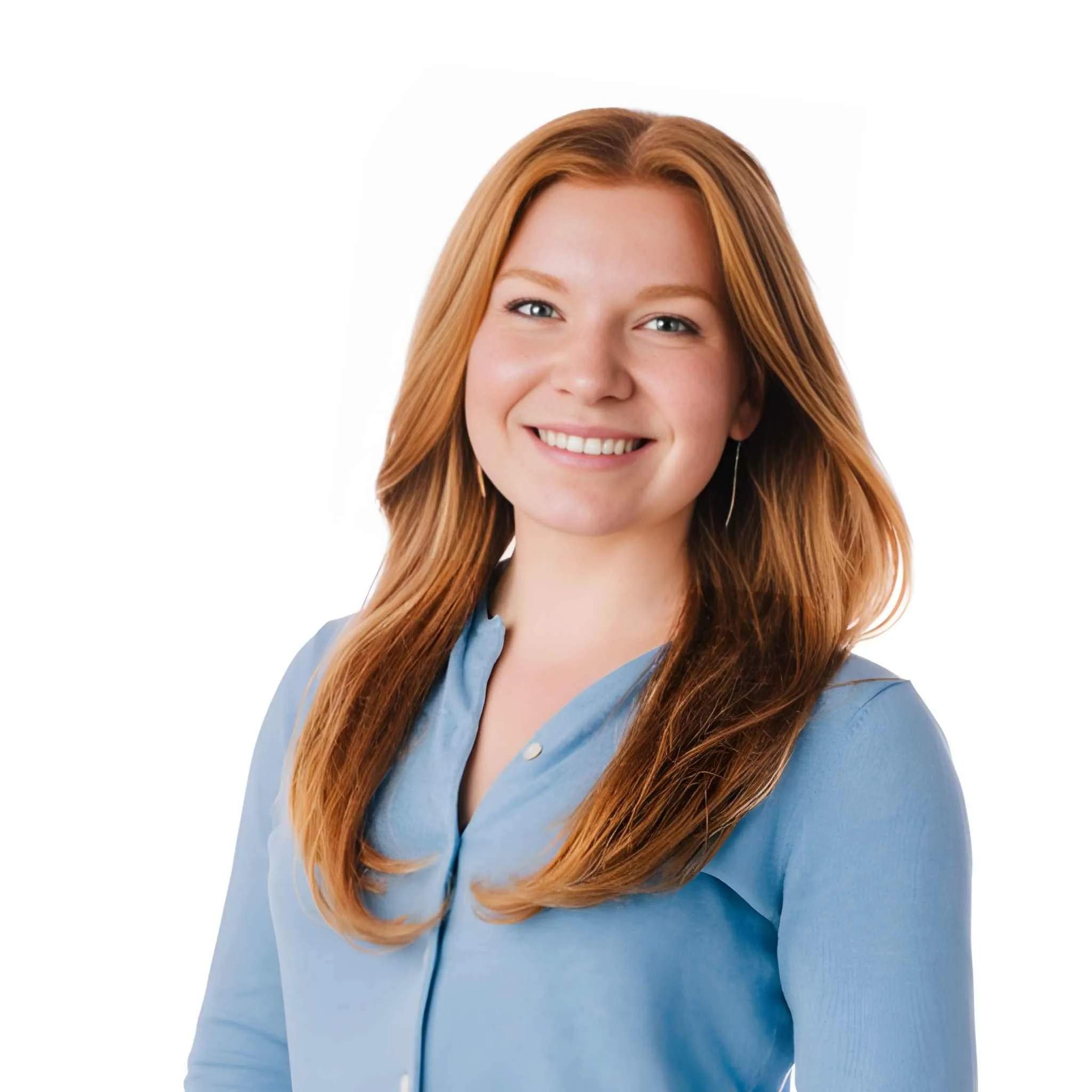 Smiling woman with long reddish hair wearing a light blue buttoned blouse against a white background.